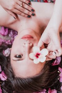 Elegant photoshoot featuring a woman holding a pink flower amidst petals.